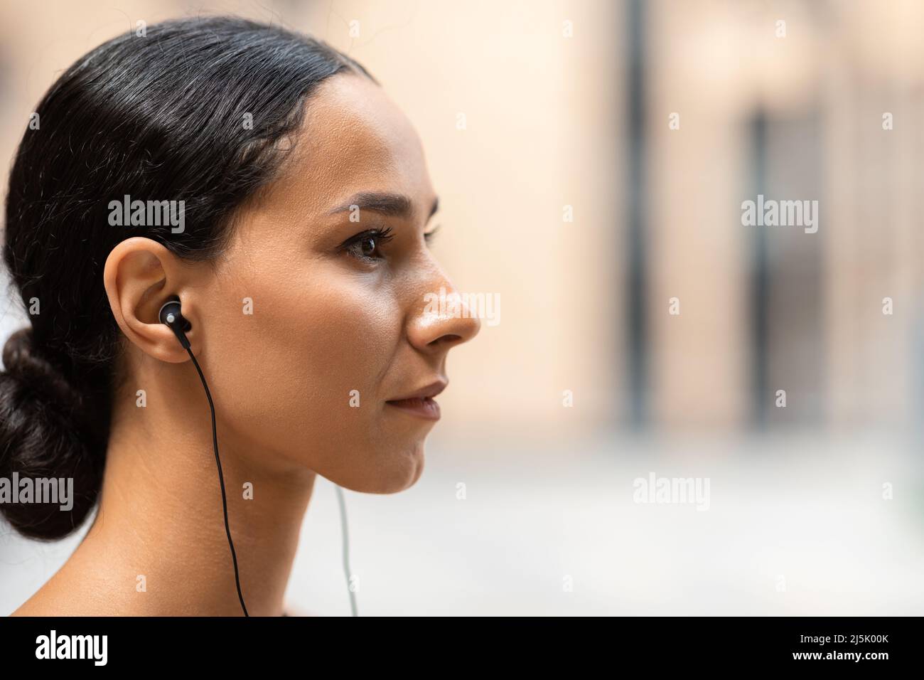 Ernst selbstbewusst junge arabische Frau Athlet Brünette in Kopfhörern auf Gebäude Hintergrund, Profil, Nahaufnahme Stockfoto