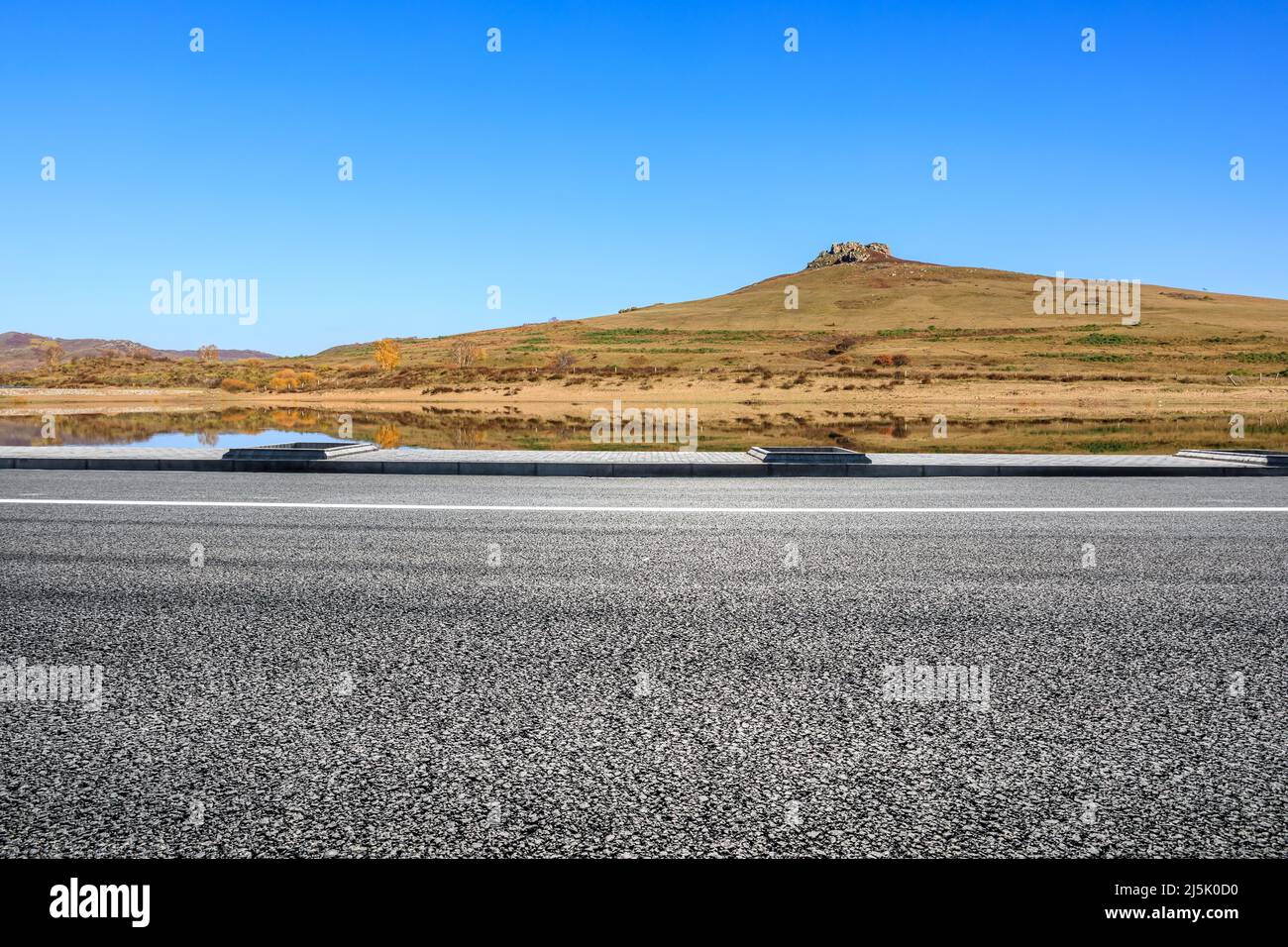Leere Asphaltstraße und Berglandschaft unter blauem Himmel Stockfoto