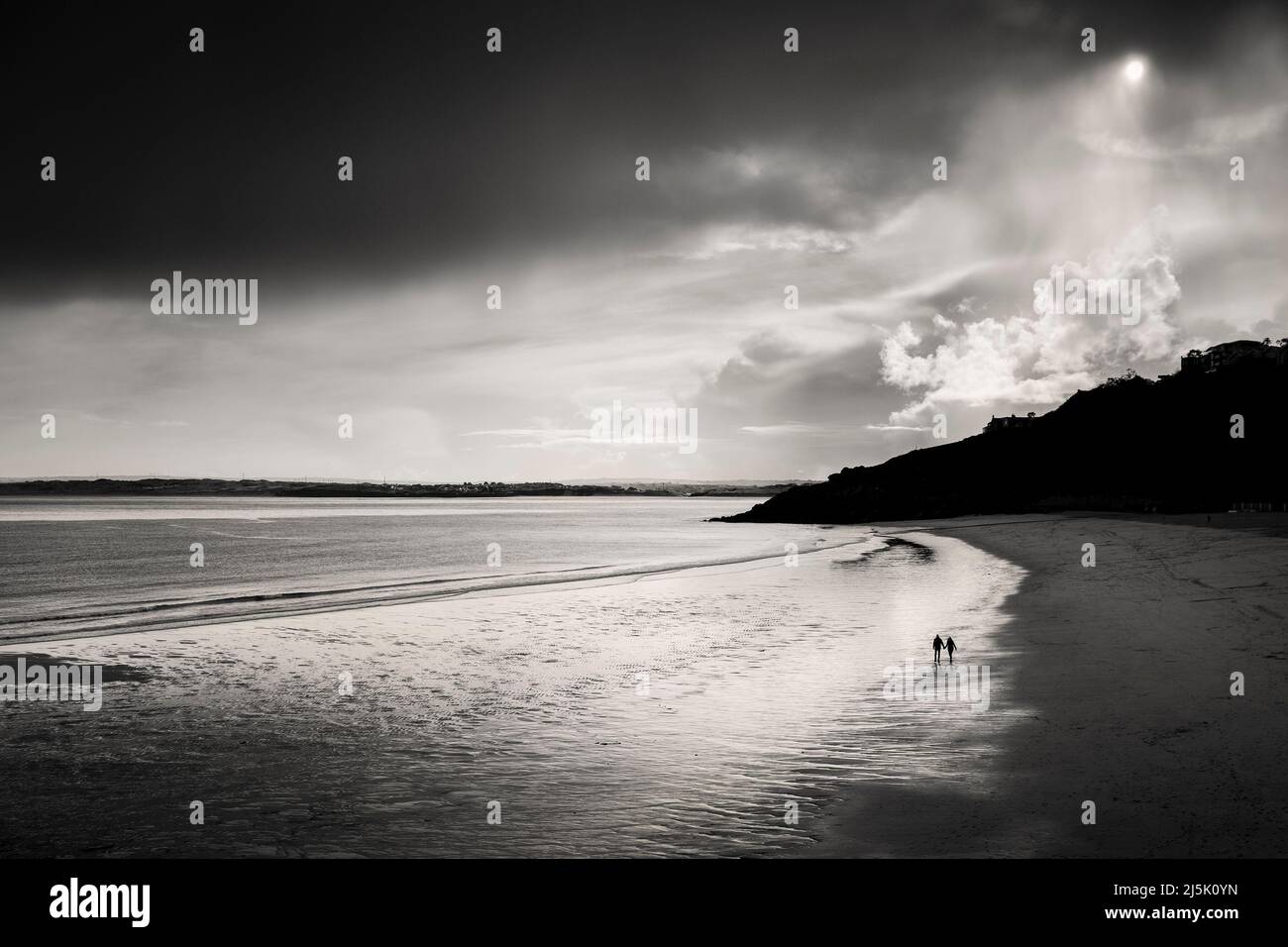 Ein Paar, das am Porthminster Beach, Cornwall, spazierengeht, launischer Himmel Stockfoto