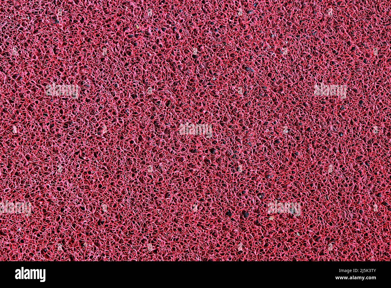 Roter synthetischer Teppich Textur Hintergrund Stockfoto