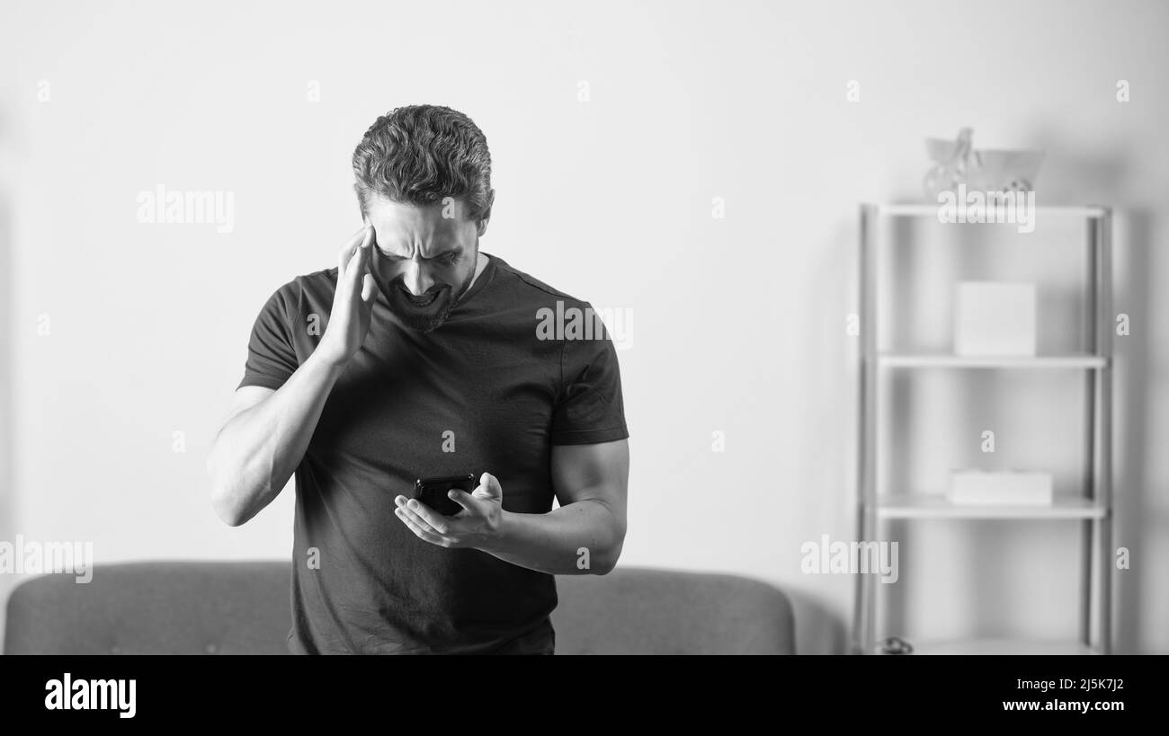 Schockierter Mann, der die Nachricht am Telefon im Büroinneren, in der Kopierfläche und in den schlechten Nachrichten las Stockfoto