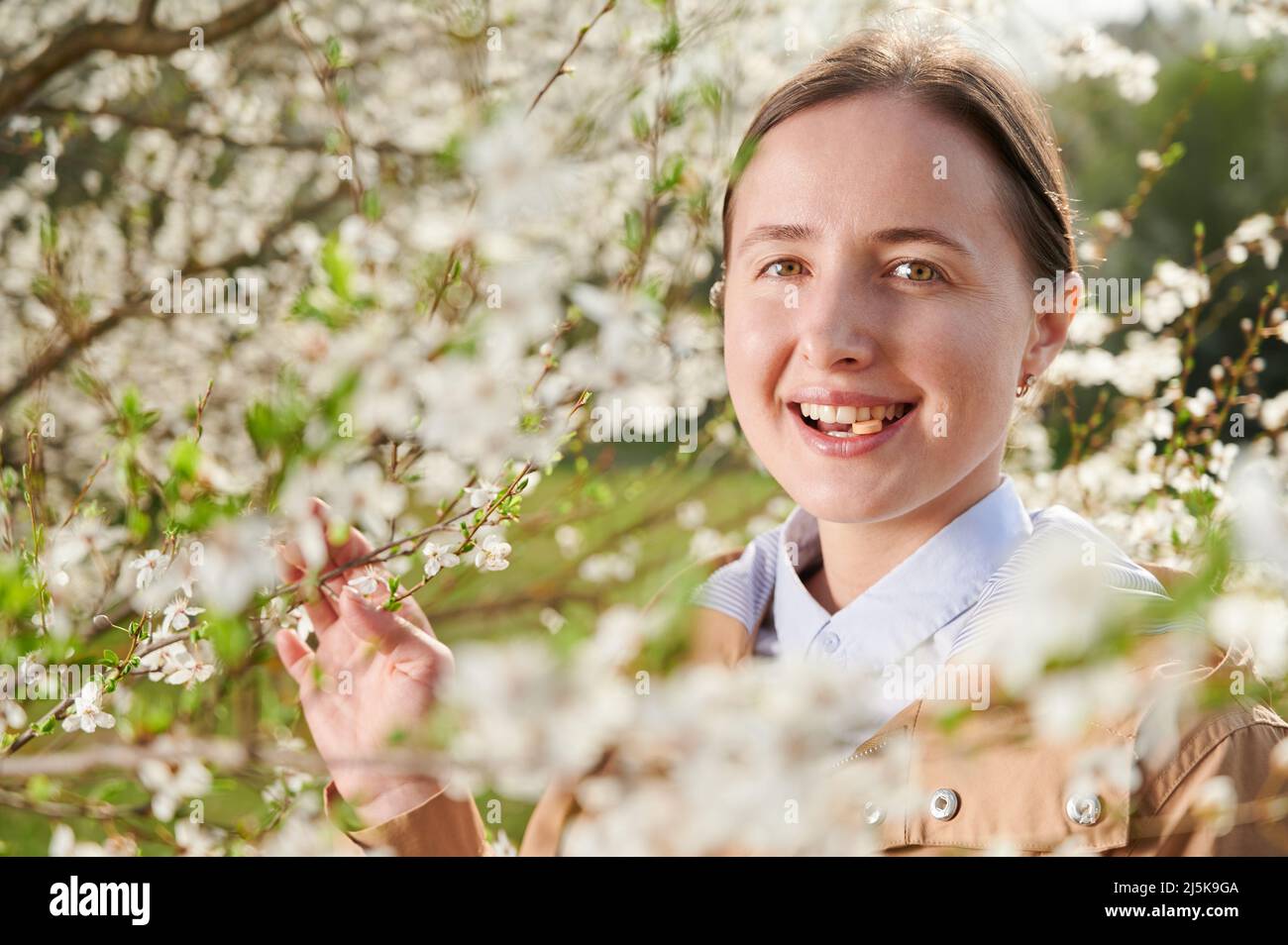 Allergische Frau, die im Frühling an einer saisonalen Allergie leidet und im Frühling im blühenden Garten posiert. Nahaufnahme einer Frau, die unter blühenden Bäumen eine Allergie-Droge verwendet. Konzept der Antihistaminika Stockfoto
