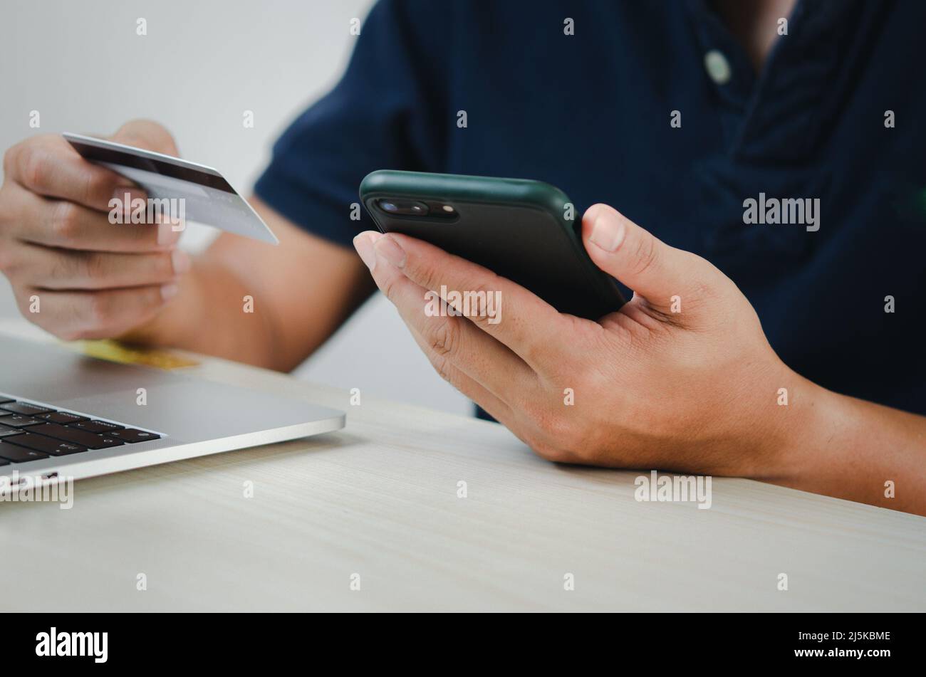 Mann Hand hält Kreditkarte und Handy Online-Shopping E-Commerce und Internet-Banking. Stockfoto
