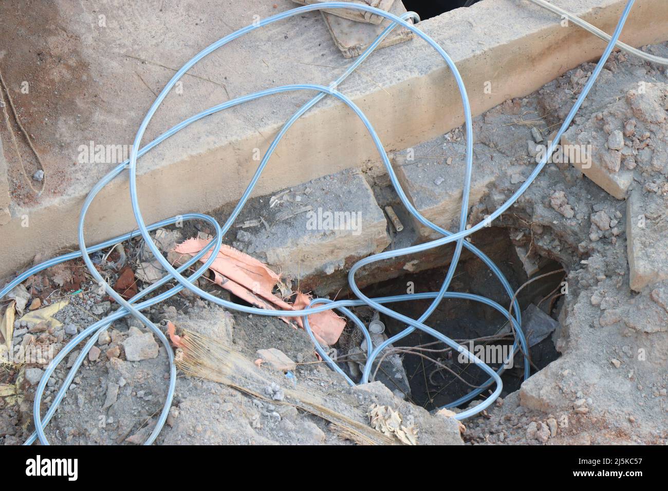 Wasserschlauch auf der Baustelle, wobei einige Teile in eine kleine Grube gefallen sind Stockfoto