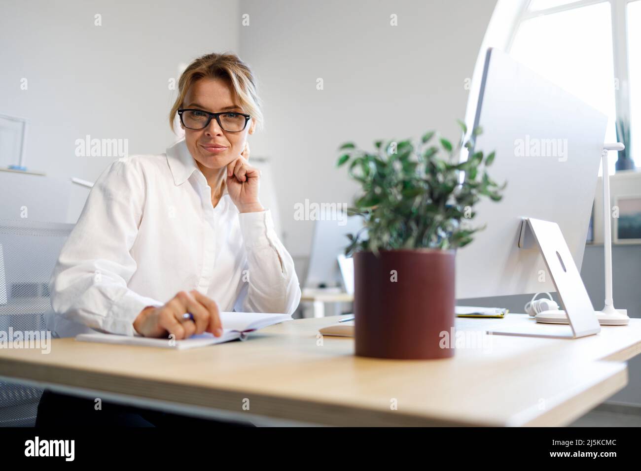 Ziemlich reife Geschäftsfrau, die im Büro sitzt Stockfoto