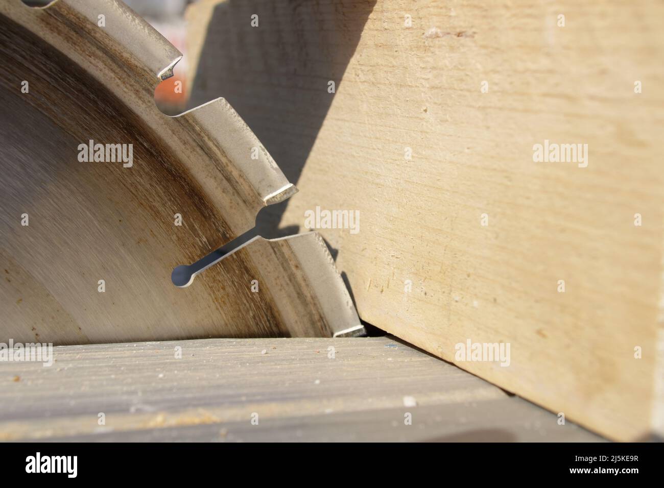Ein Stück Holz liegt am Sägeblatt einer Kreissäge an Stockfoto