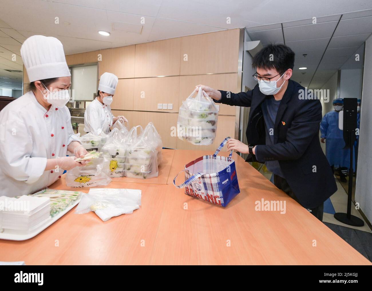 (220424) -- SHANGHAI, 24. April 2022 (Xinhua) -- Ein Mitarbeiter nimmt Essen für seine Abteilung in der Kantine des Gebäudes der Bank of China in Shanghai, Ostchina, am 20. April 2022. Angesichts der Herausforderungen, die durch das Wiederaufleben der COVID-19 in Shanghai verursacht wurden, konnten Finanzinstitute und Banken ihre Arbeit weiter aufnehmen. Die Niederlassung der Bank of China in Shanghai hat ein temporäres Closed-Loop-Management für diensthabende Mitarbeiter eingeführt, die von einem effizienten Logistik-Support-Team unterstützt werden. Das Team besteht aus drei Mitgliedern: dem stellvertretenden Generaldirektor Wang Lianghui, dem Direktor Han Hao und dem Mitarbeiter Xue Feng. Der Tee Stockfoto