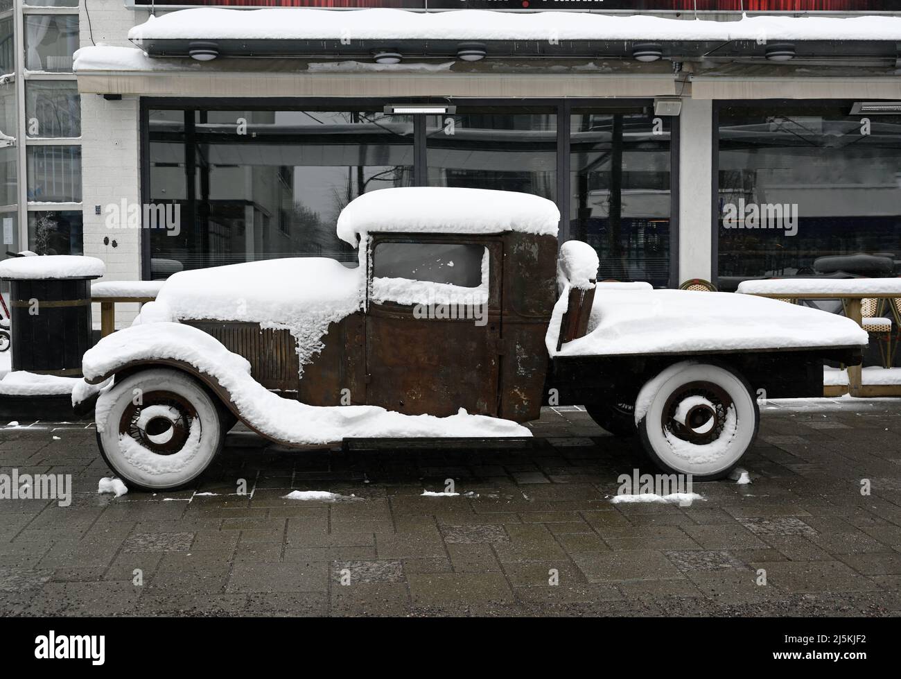 Altes rostiges Retro-Auto, das draußen mit Schnee bedeckt ist Stockfoto