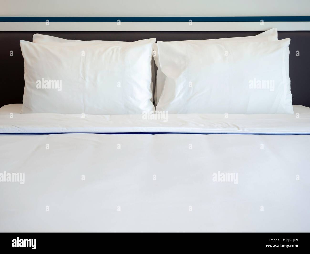 Vier weiße, saubere Kissen, eine Decke und ein Leinenbetttuch im Hotelzimmer mit Platz für Kopien. Bettwäsche im Schlafzimmer, Vorderansicht. Stockfoto