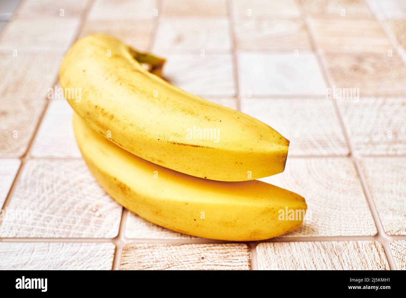 Zwei reife Bananen auf einer karierten Holzoberfläche Stockfoto