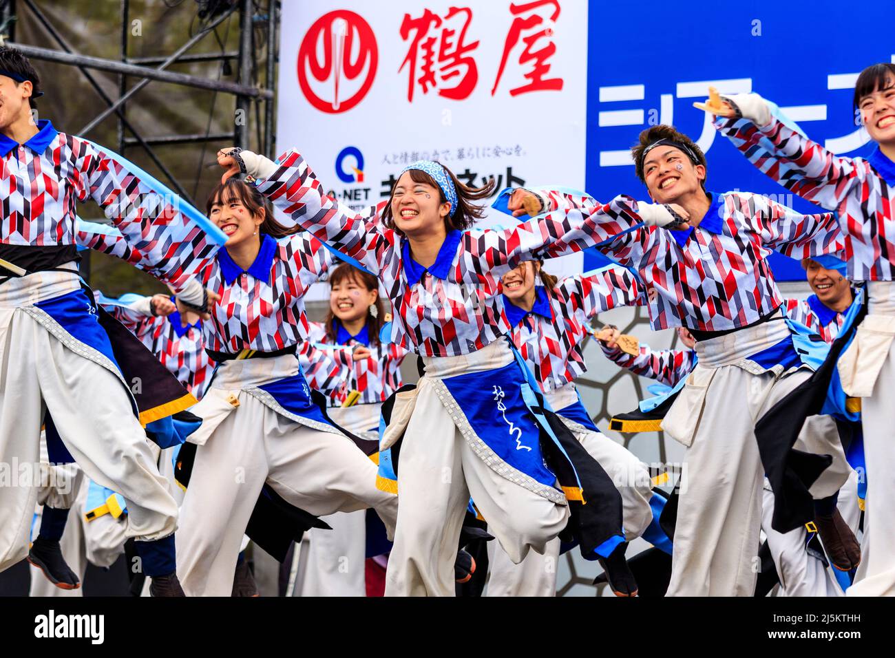 Japanisches Team von Yosakoi-Tänzern, die in Yukata-Tuniken tanzen und Naruko, Klatschen, auf der Freiluftbühne des Kyusyu Gassai Festivals in Kumamoto halten. Stockfoto