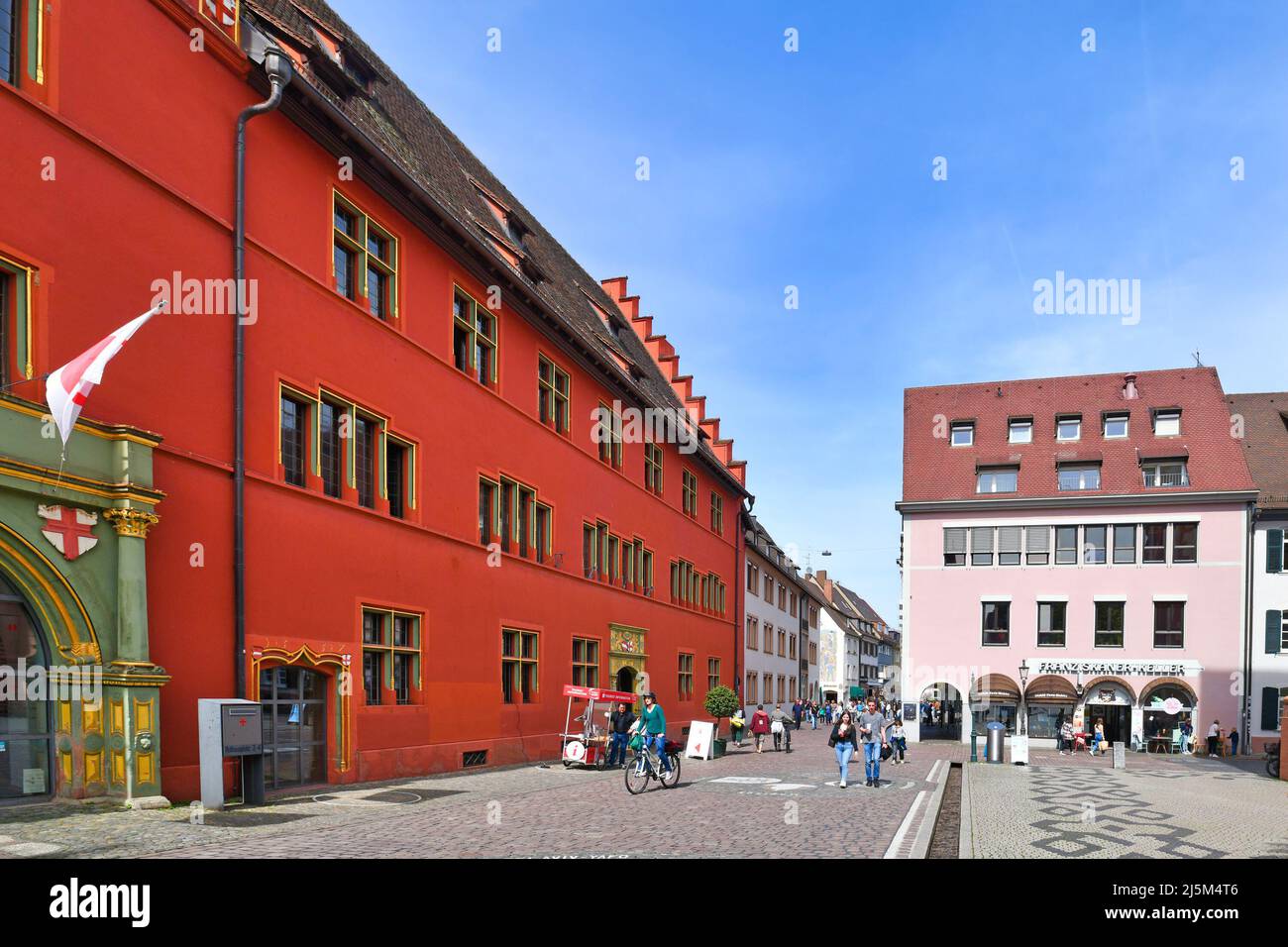 Freiburg, Deutschland - April 2022: Leuchtendes rotes Gebäude der Touristeninformation am Rathausplatz Stockfoto