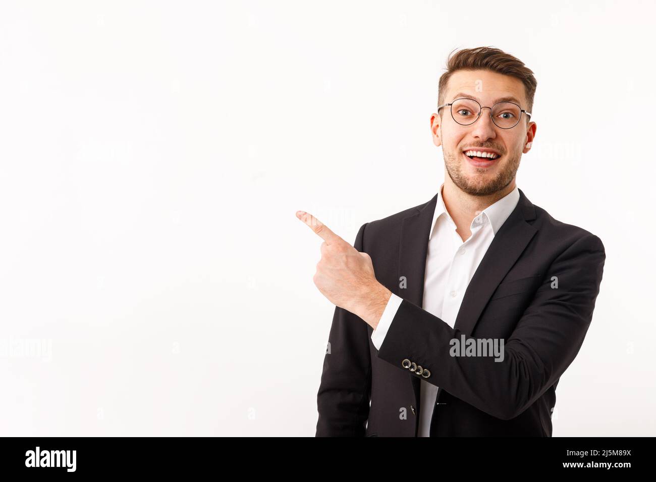 Ein junger Geschäftsmann in einem Geschäftsanzug weist auf Copyspace hin. Stockfoto
