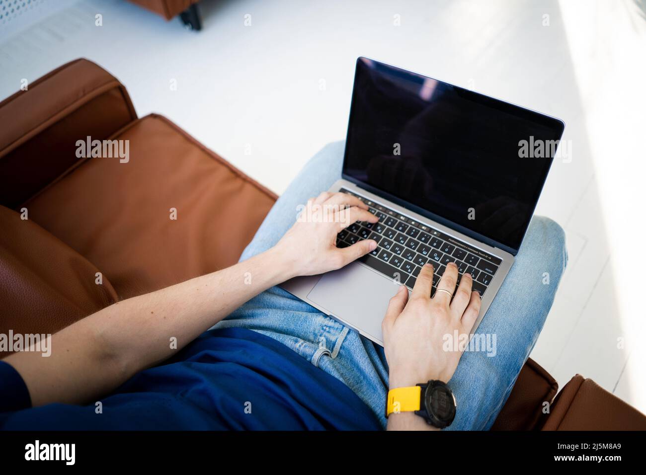 Freier Mann, der an einem Laptop arbeitet, der auf einem Stuhl sitzt Stockfoto