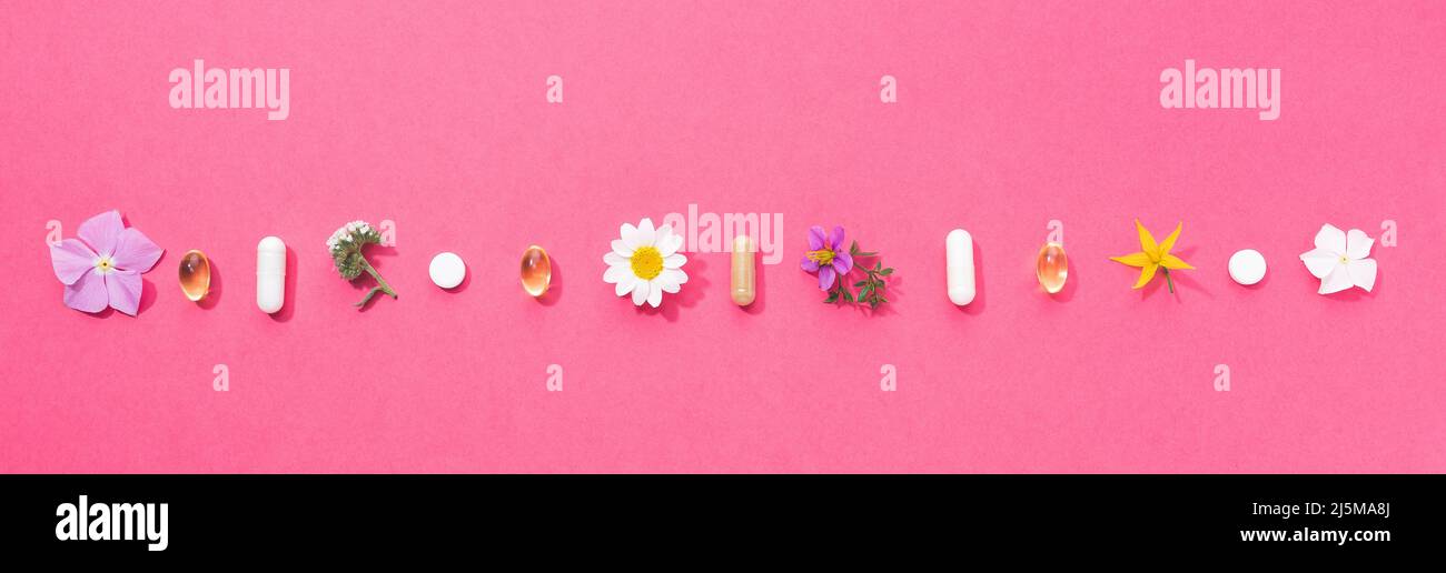 Vitaminkapseln und Nahrungsergänzungsmittel isoliert auf rosa Hintergrund. Panoramaformat. Stockfoto