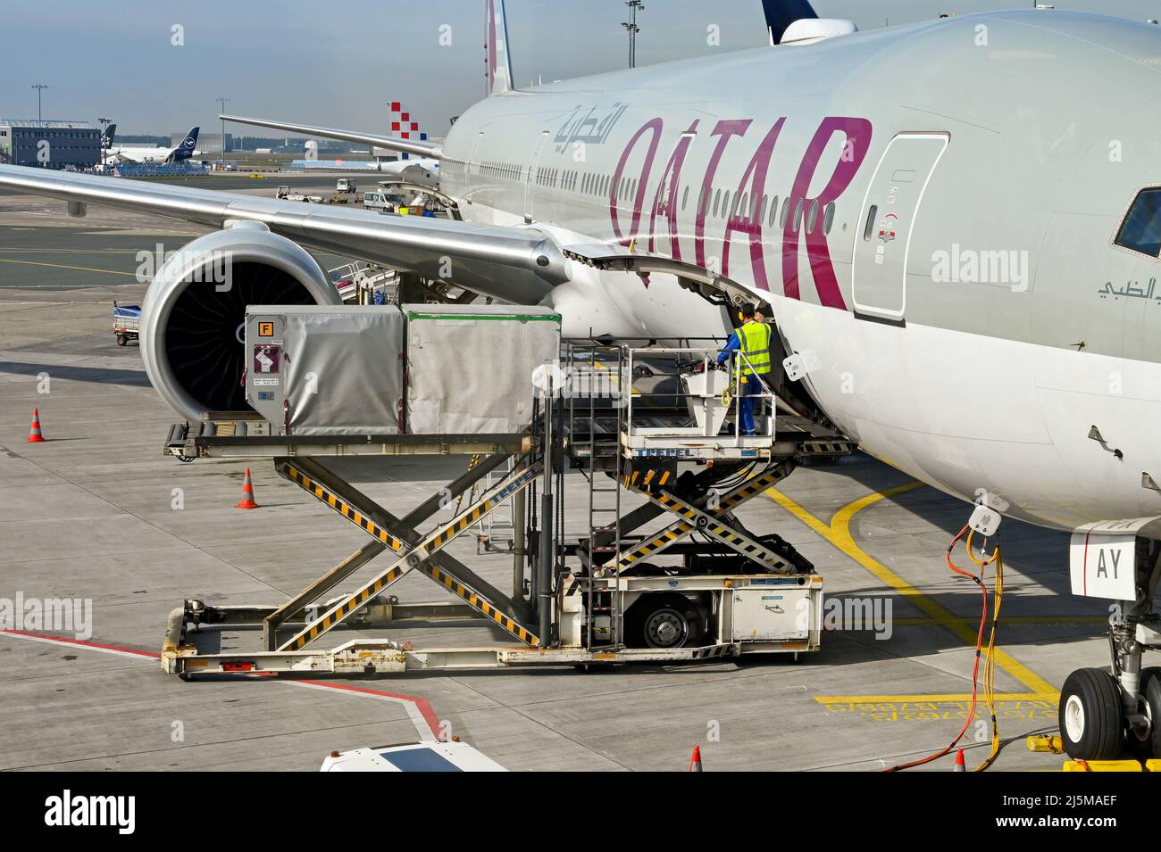 Frankfurt, Deutschland - April 2022: Flughafenmitarbeiter beladen Container mit einem Luftfrachtpalettenlader in den offenen Frachtraum eines Qatar Airways-Jet Stockfoto