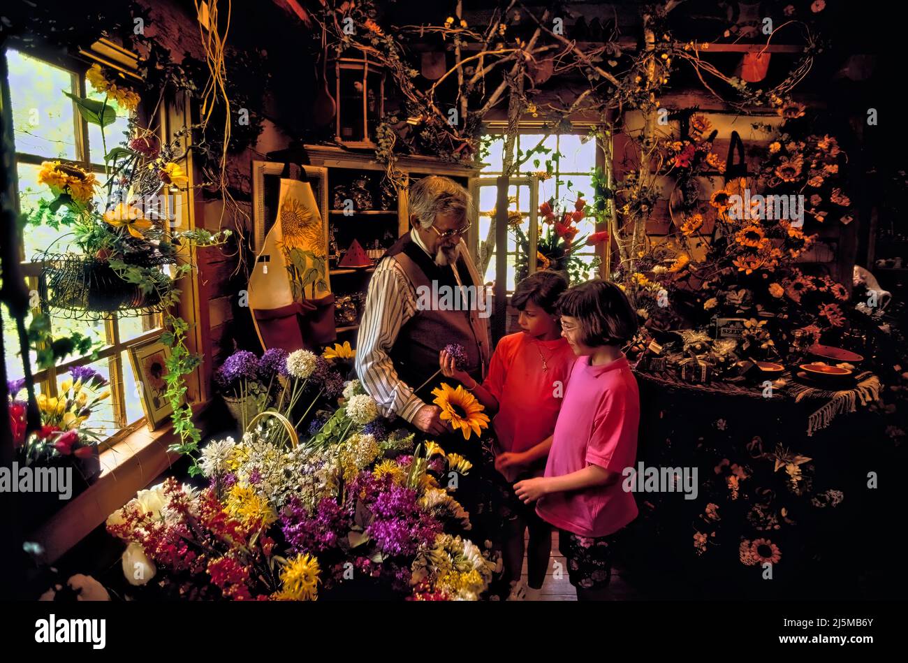 Branson, Missouri USA 19. April 1992: Ein Florist zeigt zwei jungen Käufern ein Blumenmuster im Blumengeschäft in Silver Dollar City. Stockfoto