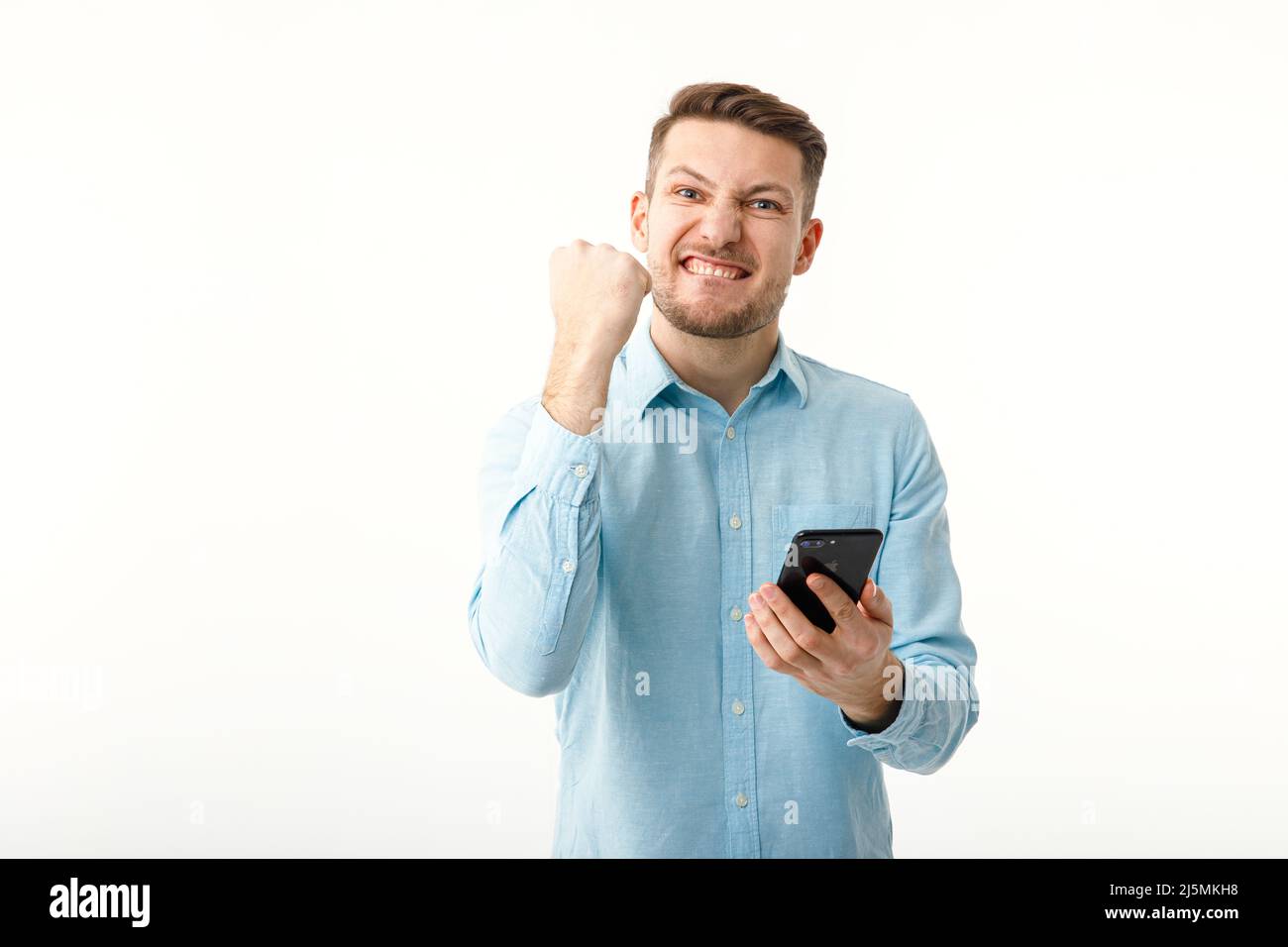 Ein Geschäftsmann hält ein Smartphone und freut sich über eine erfolgreiche Transaktion. Telearbeit, freiberuflich. Stockfoto