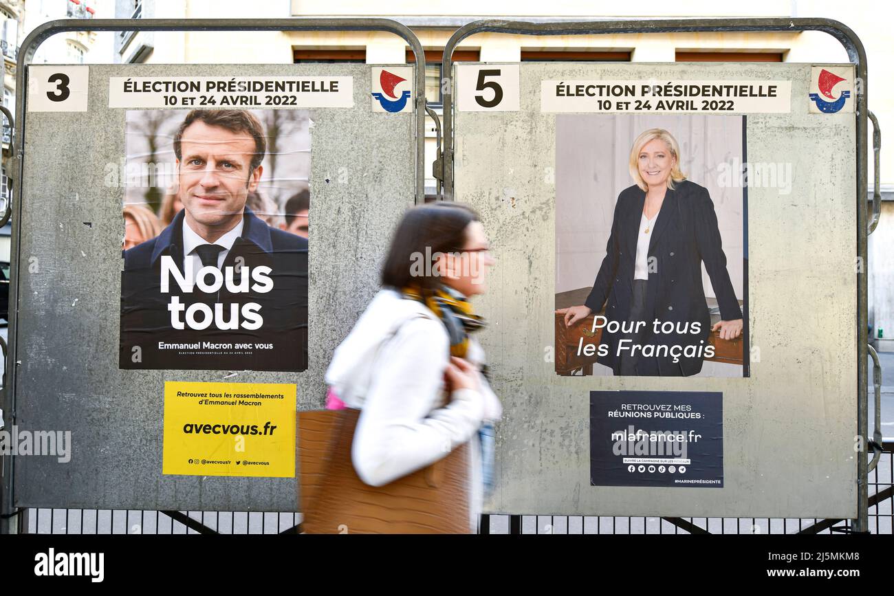 Paris, Frankreich. 24. April 2022. Ein Fußgänger übergibt offizielle Wahlkampfplakate auf einer Wahlplakatwand (Schild). Präsidentschaftsplakate auf ihren Wahlvorständen. Abbildung am 24. April 2022 in Paris, Frankreich. Die französischen Wähler kommen an die Wahlen, um für die zweite Runde der Präsidentschaftswahlen zu stimmen, um ihren neuen Präsidenten der Republik zwischen Emmanuel Macron (LREM) und Marine Le Pen (RN, 'Rassemblement National') zu wählen. Kredit: Victor Joly/Alamy Live Nachrichten Stockfoto