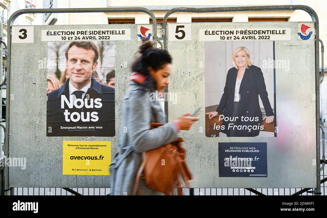 Paris, Frankreich. 24. April 2022. Ein Fußgänger übergibt offizielle Wahlkampfplakate auf einer Wahlplakatwand (Schild). Präsidentschaftsplakate auf ihren Wahlvorständen. Abbildung am 24. April 2022 in Paris, Frankreich. Die französischen Wähler kommen an die Wahlen, um für die zweite Runde der Präsidentschaftswahlen zu stimmen, um ihren neuen Präsidenten der Republik zwischen Emmanuel Macron (LREM) und Marine Le Pen (RN, 'Rassemblement National') zu wählen. Kredit: Victor Joly/Alamy Live Nachrichten Stockfoto