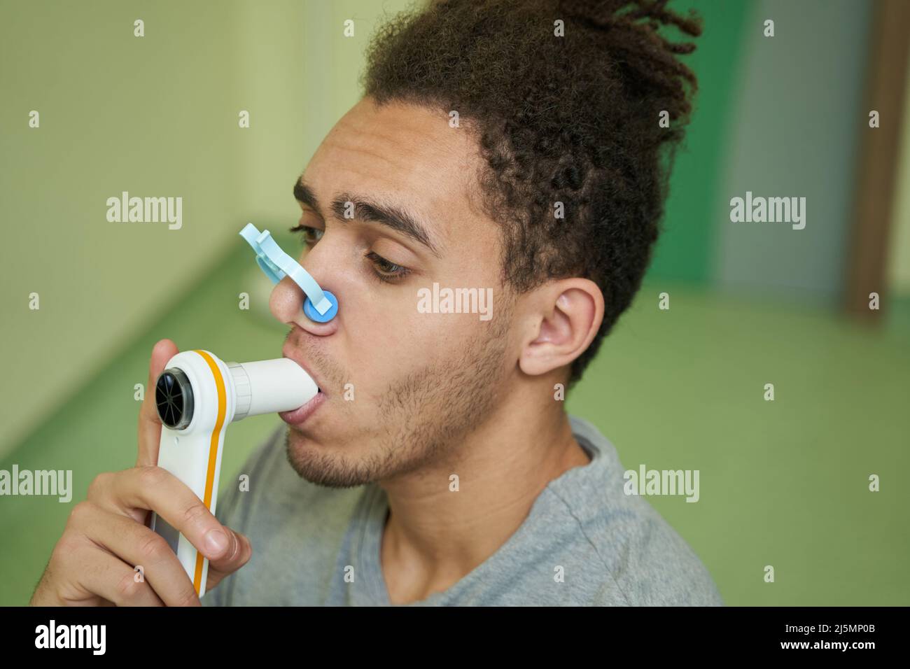 Männlich hält das Mundstück des Spirometers im Mund Stockfoto