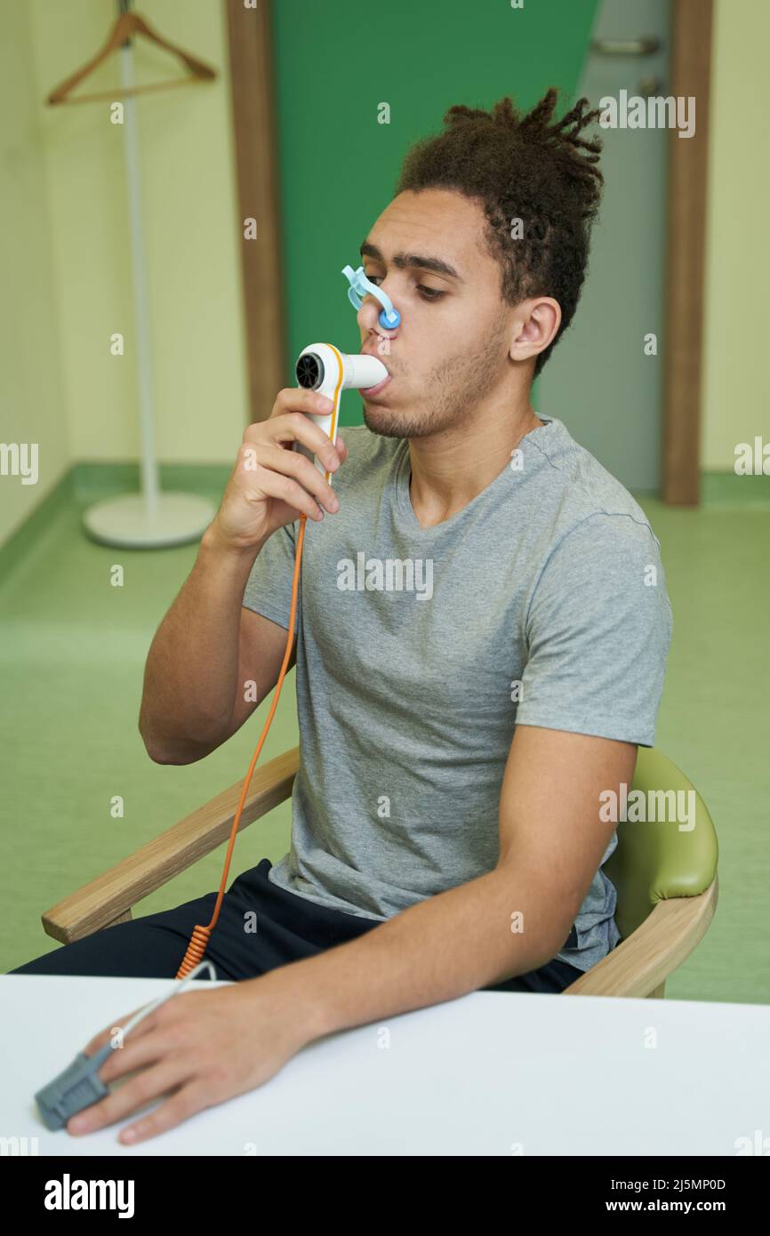 Mann atmet während des Tests in den Schlauch des Spirometers ein Stockfoto