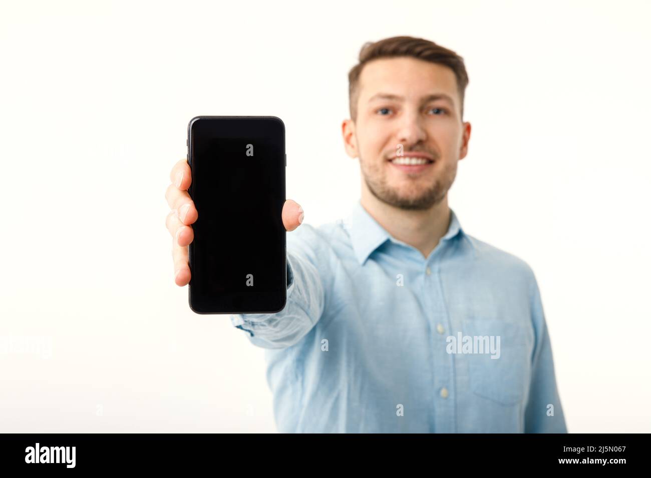 Der Mann zeigt auf dem Copyspace-Bildschirm des Smartphones. Isoliert auf weißem Hintergrund. Stockfoto
