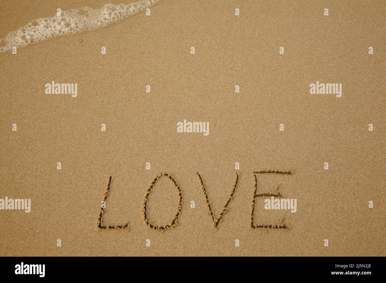 Liebe - handgeschrieben auf dem weichen Strandsand. Stockfoto