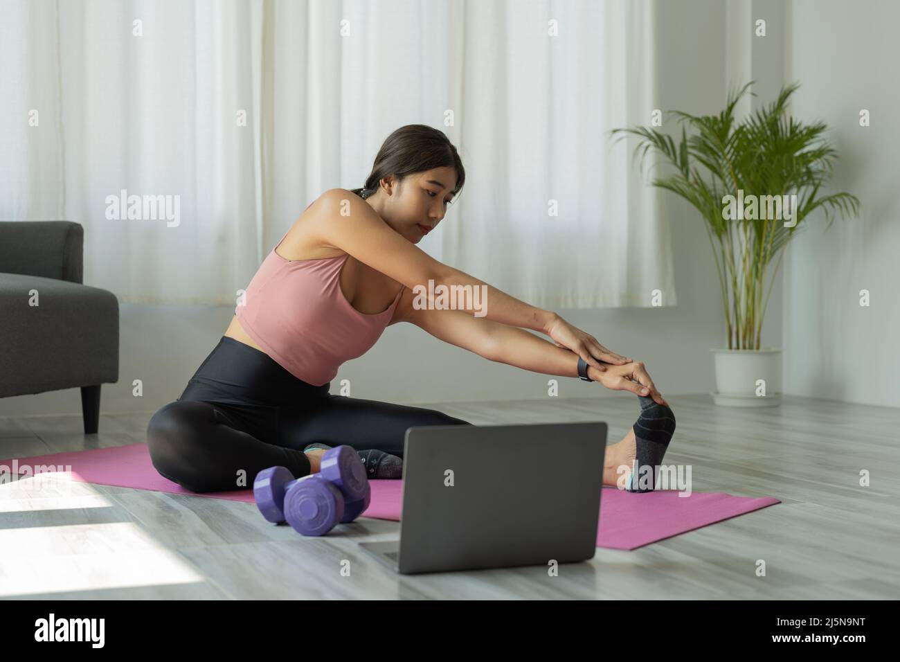 Die junge Frau trainiert zu Hause Yoga. Fitness, Training, gesundes Leben und Diät-Konzept Stockfoto