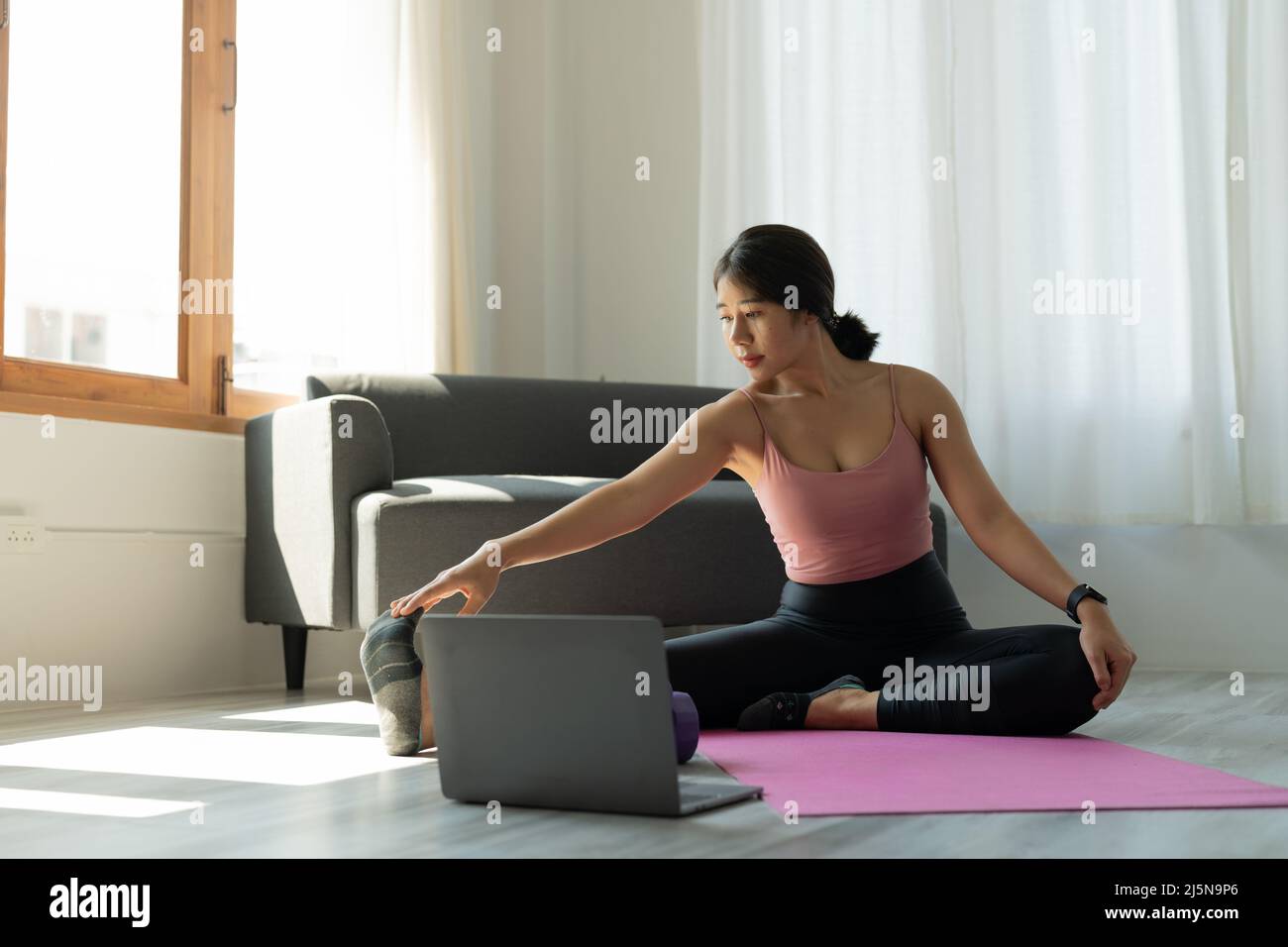 Die junge Frau trainiert zu Hause Yoga. Fitness, Training, gesundes Leben und Diät-Konzept Stockfoto