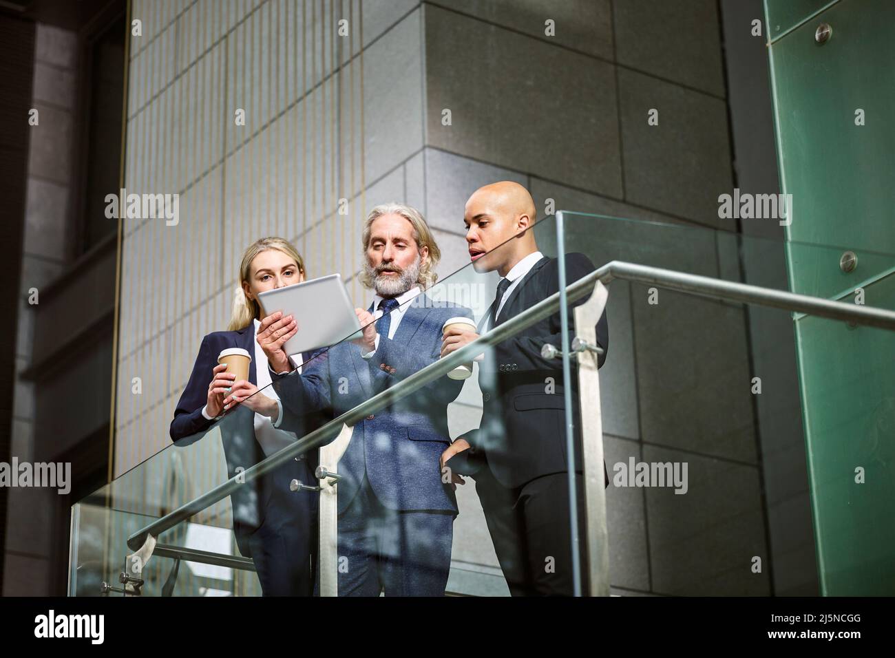 Multinationalen und multiethnischen corporate Menschen diskutieren Geschäft mit digitalen Tablet in der modernen Bürogebäude, Low Angle View. Stockfoto