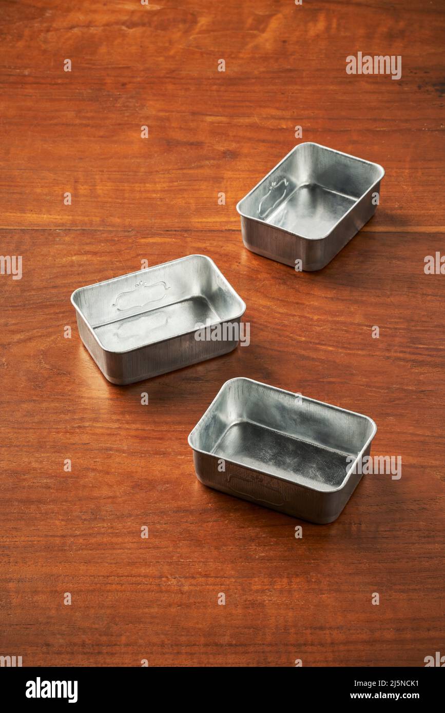Drei Lebensmittelverpackungen aus Dosen liegen willkürlich auf einem Holztisch Stockfoto