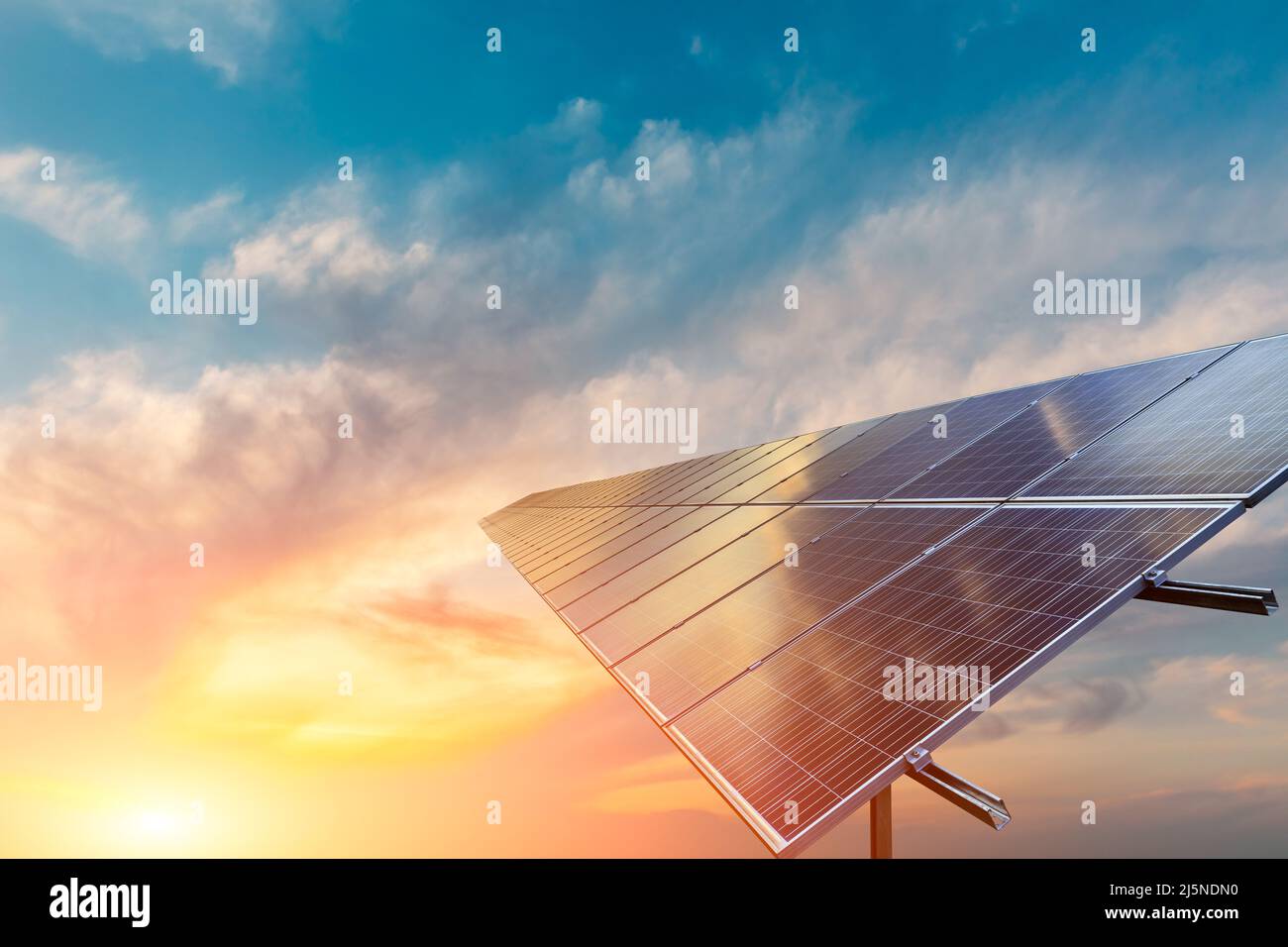 Sonnenkollektoren und wunderschöne Sonnenuntergangswolken. Konzept der grünen Energie. Stockfoto