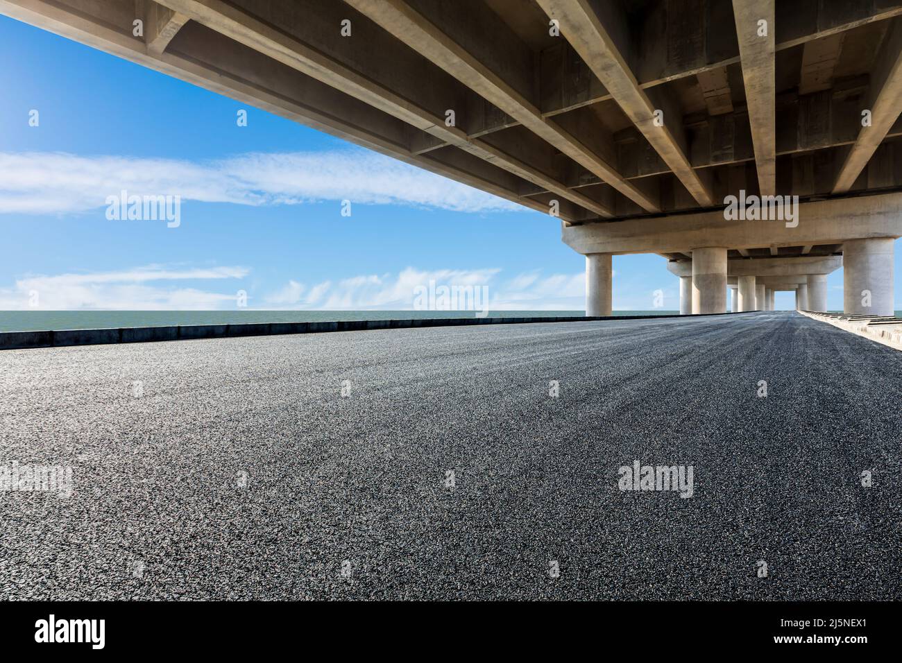 Asphaltstraße und Brücke mit Fluss unter blauem Himmel Stockfoto