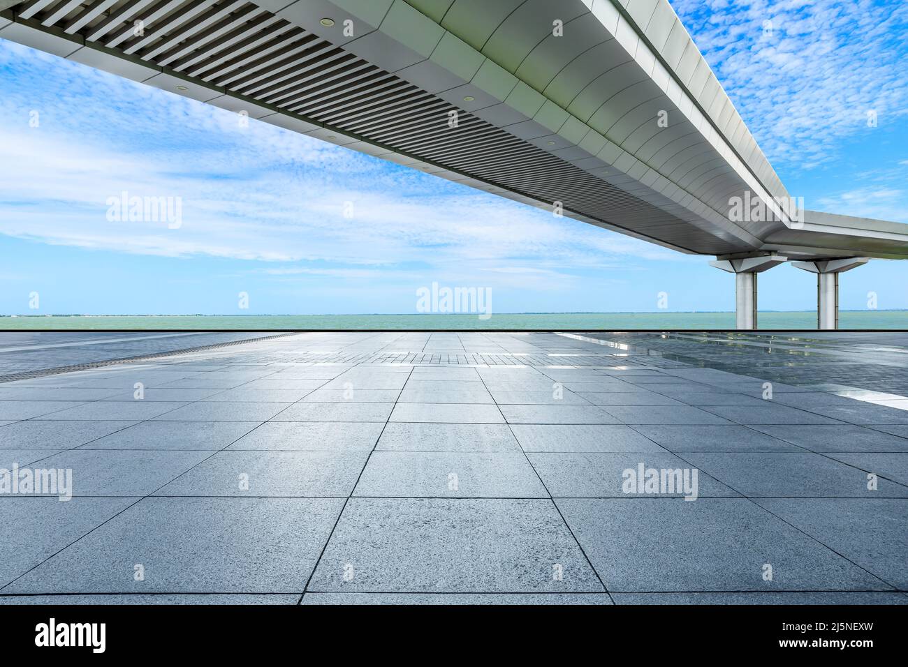 Leerer quadratischer Boden und Brücke mit Fluss unter blauem Himmel Stockfoto