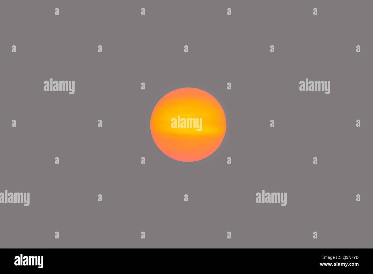 Orangefarbene Sonnenscheibe isoliert am rauchigen Himmel Stockfoto