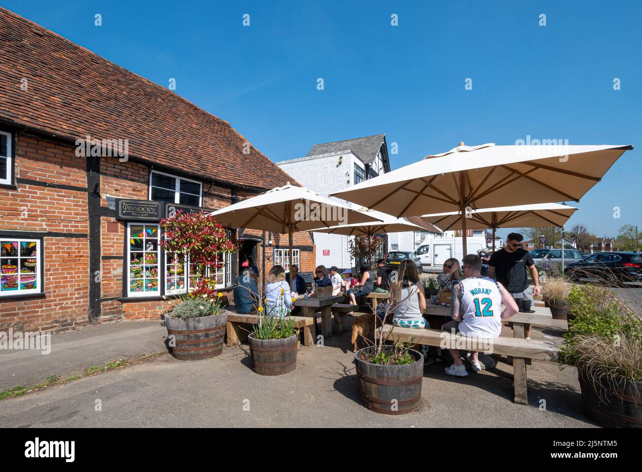 Pinnock's Coffee Shop in Ripley Village High Street, Surrey, England, Großbritannien, mit Leuten, die an einem sonnigen Tag an Tischen draußen sitzen Stockfoto