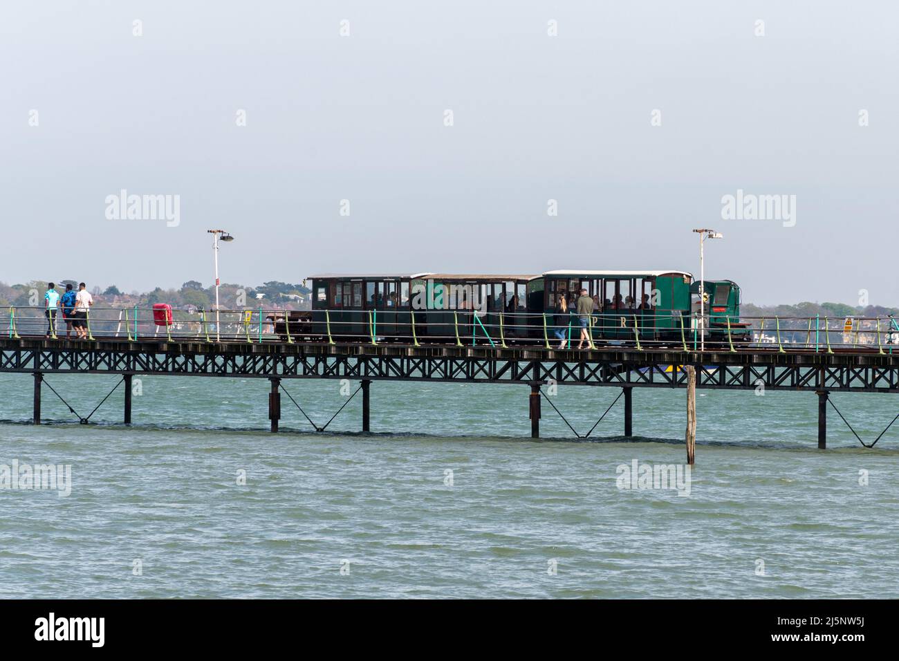 Hythe Pier mit einem Zug voller Passagiere, der zum Fährschiff fährt, das von Hythe nach Southampton in Hampshire, England, Großbritannien, fährt Stockfoto