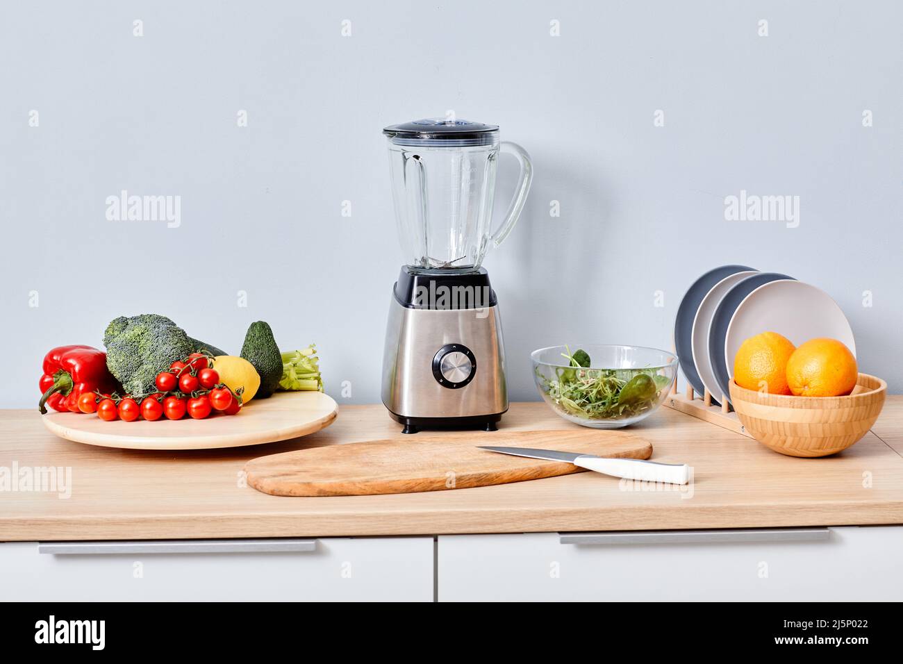 Frisches Obst und Gemüse mit modernem automatischen Mixer auf dem Tisch für die Zubereitung von Smoothie und Saft Stockfoto