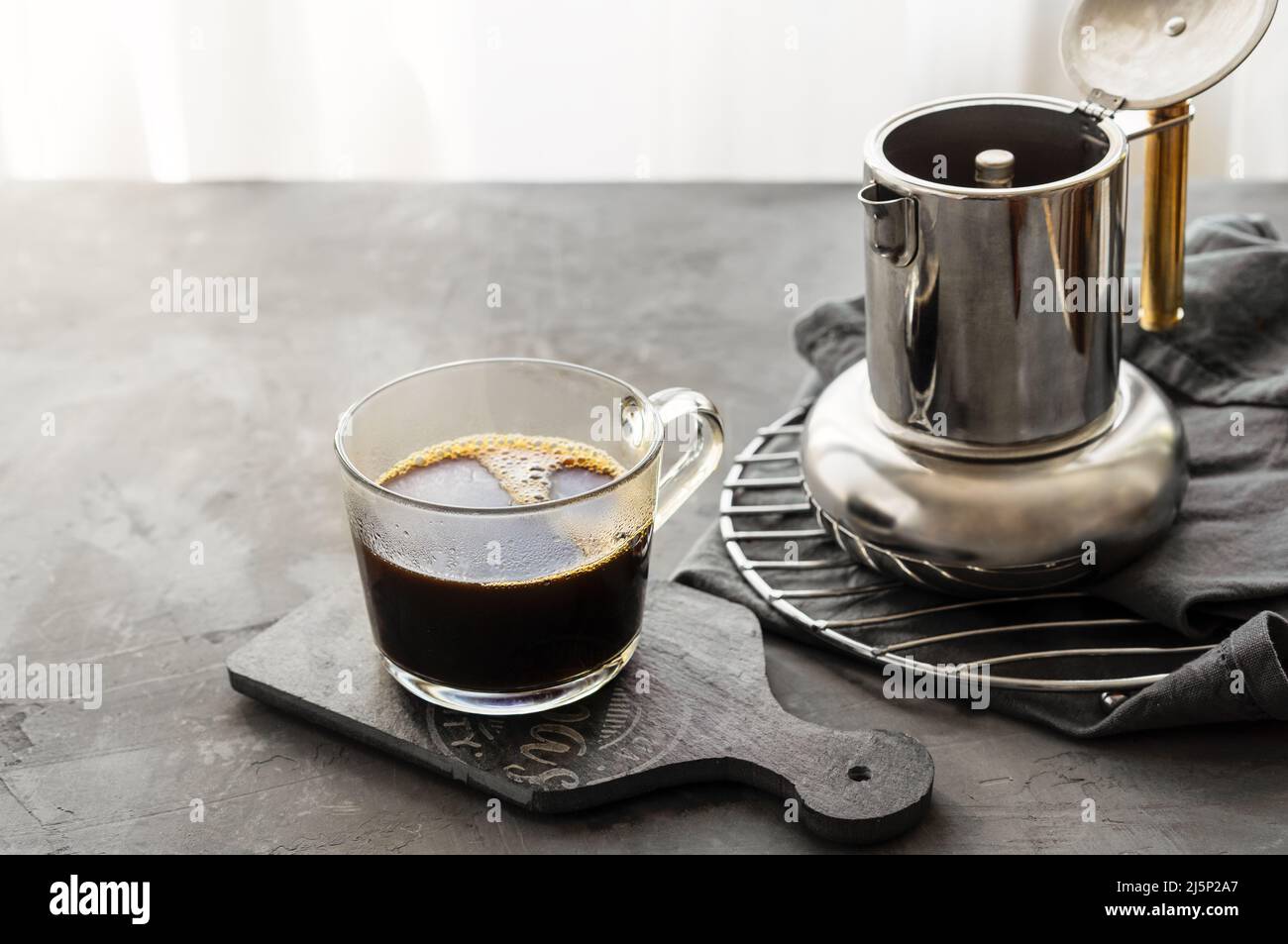 Frisch gebrühter Kaffee in Tasse und Kaffeekocher auf grauem Hintergrund Stockfoto