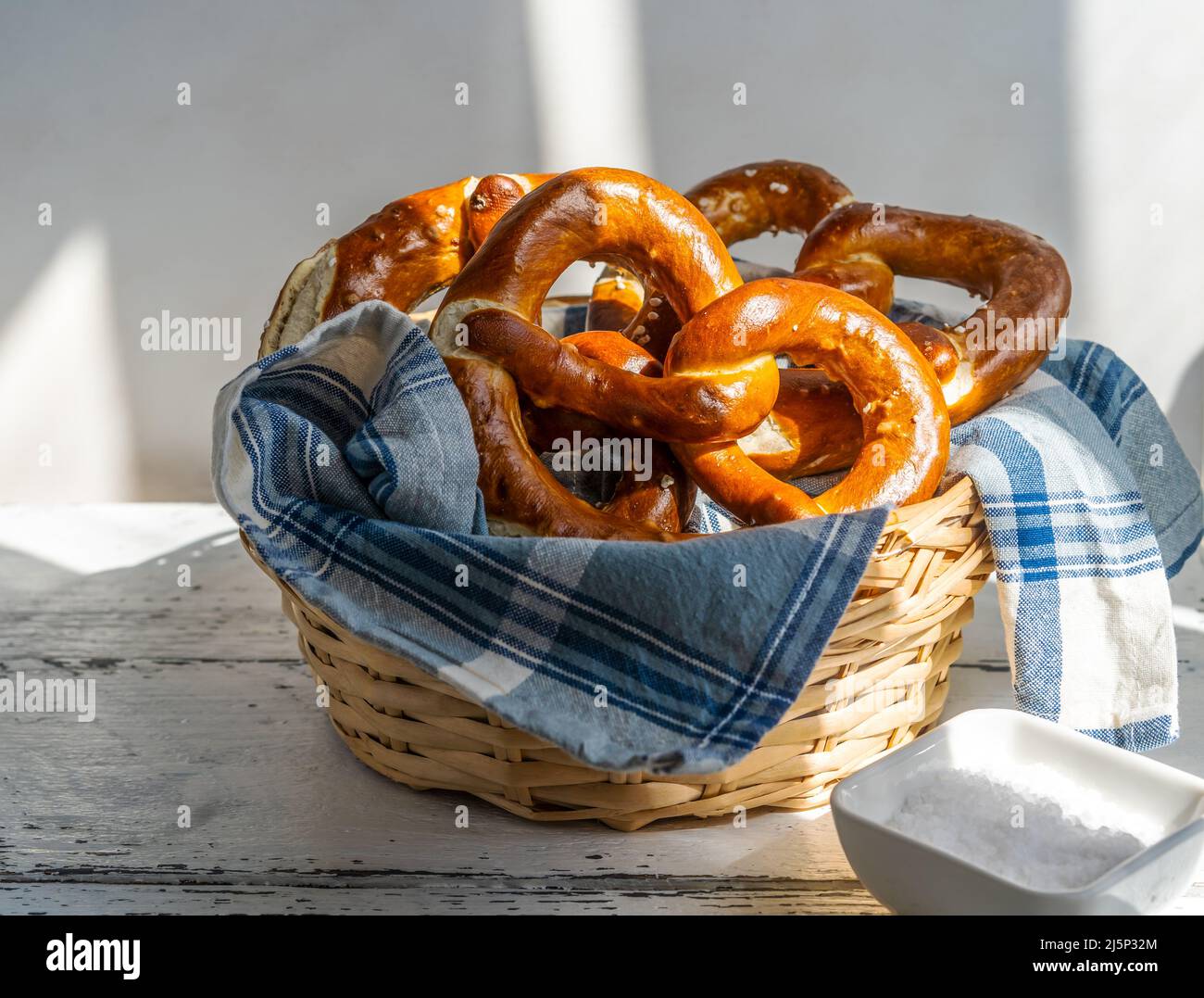 Brezeln oder Brezeln im Brotkorb mit Serviette und Salz. Starke Schatten Stockfoto