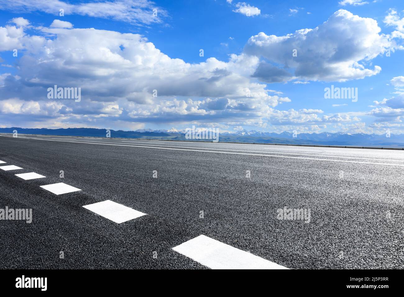 Asphaltstraße und Berglandschaft unter blauem Himmel Stockfoto