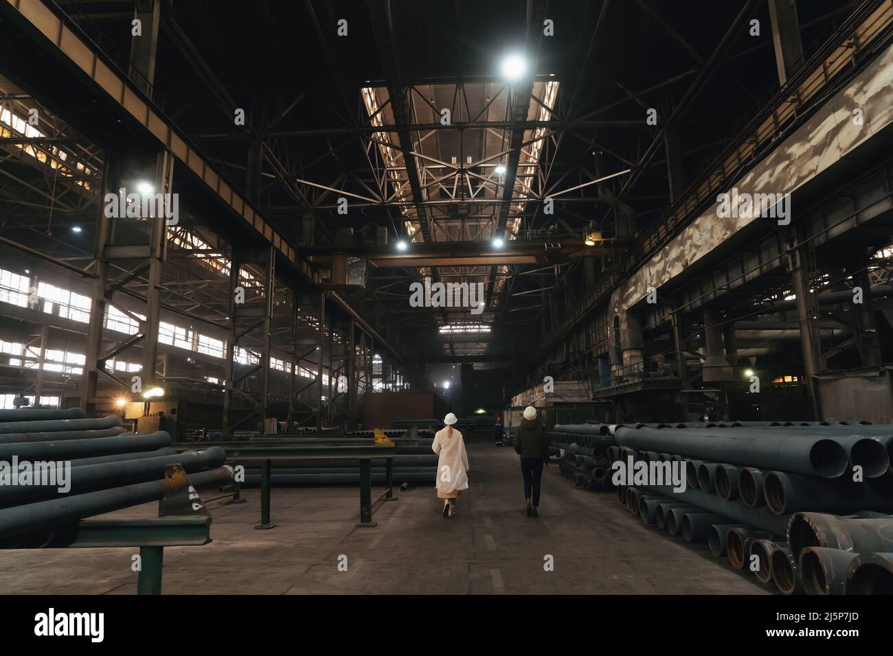 Zwei Arbeiterinnen in Hartmützen, Seitenansicht im Inneren des großen Fabriklagers. Stockfoto