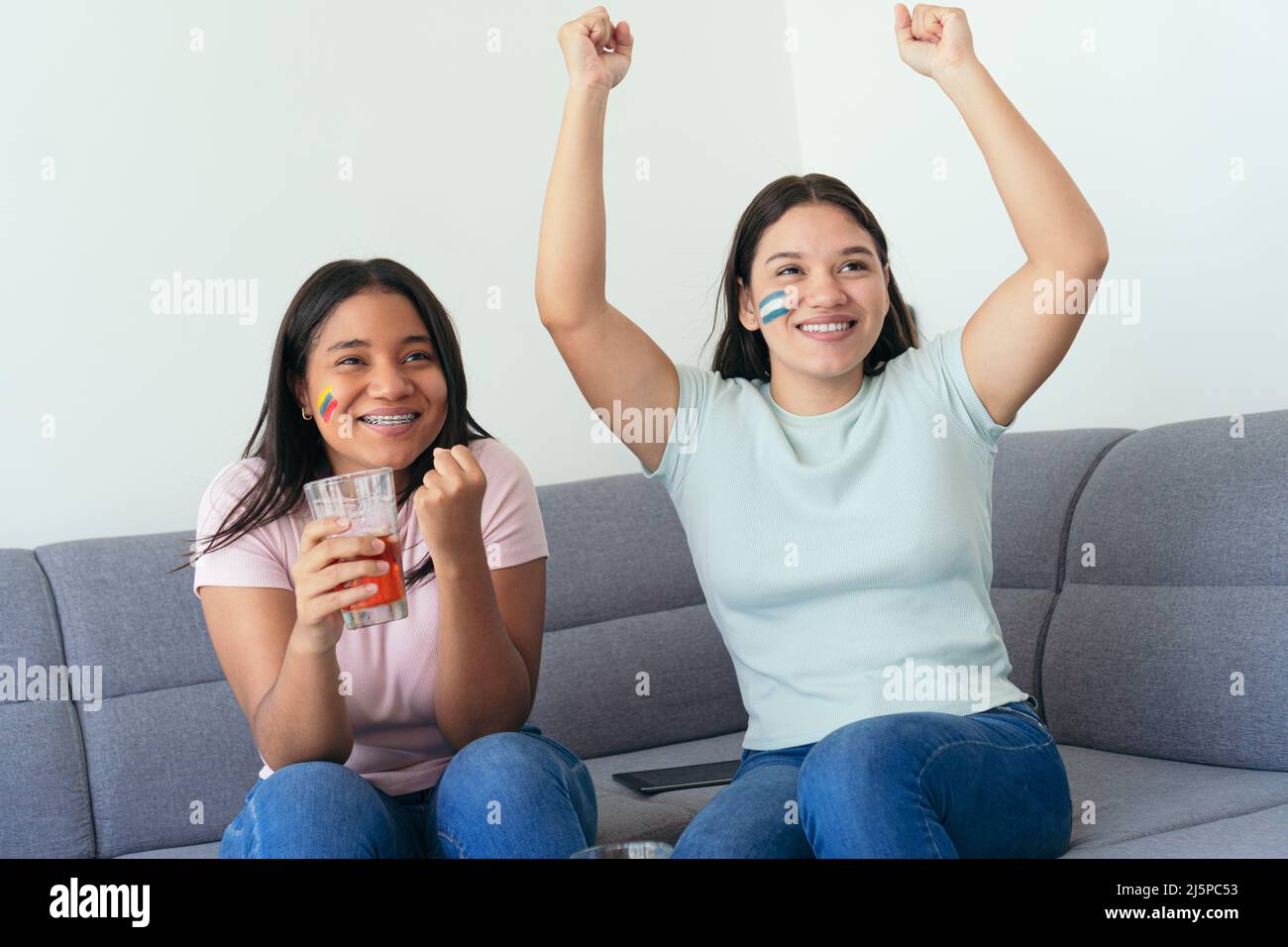 Lateinamerikanische Freundinnen, die sich zu Hause ein Fußballspiel ansehen Stockfoto