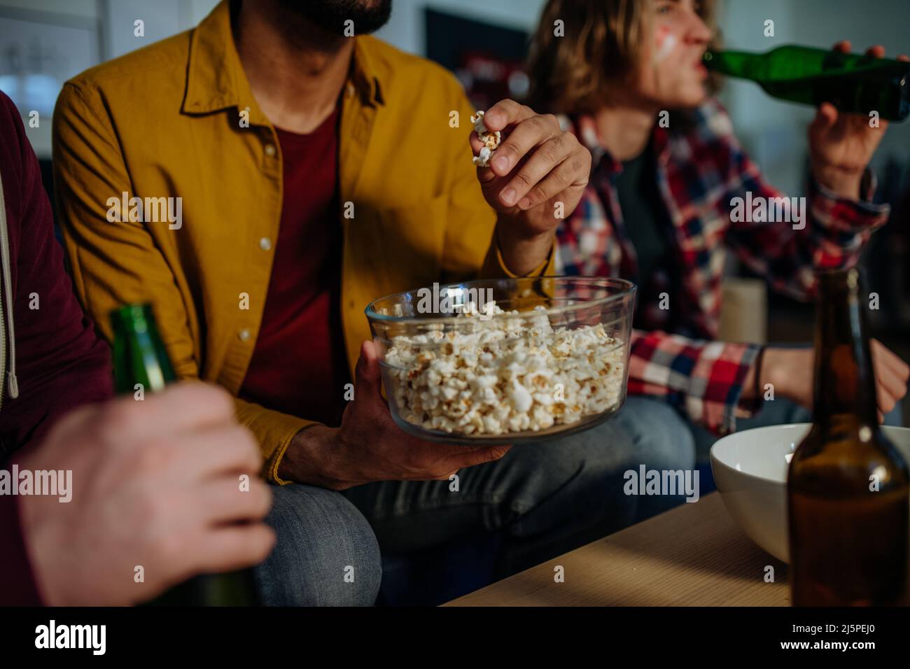 Nahaufnahme der Freunde von Fußballfans, die ein Spiel ansehen und Popcorn essen. Stockfoto