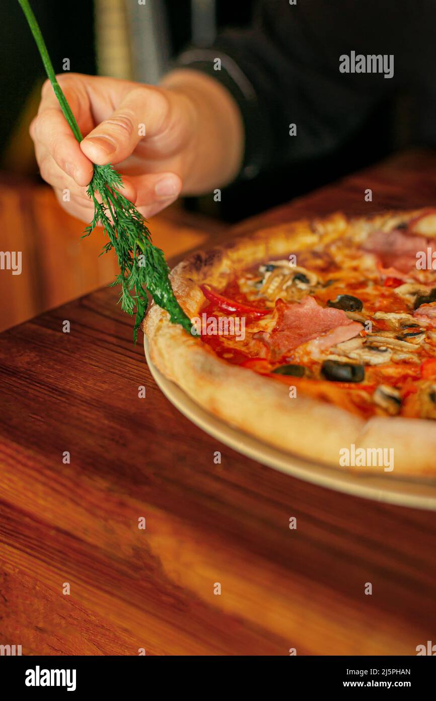 Pizza Vorbereitung Ölen von Dill Öl bereit Pizza. Männliche Hand Stockfoto