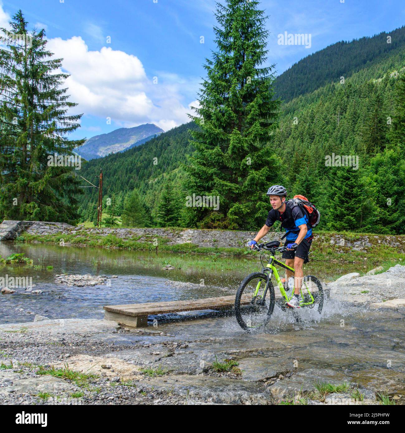 Junger Radfahrer überquert kleinen Bach Stockfoto