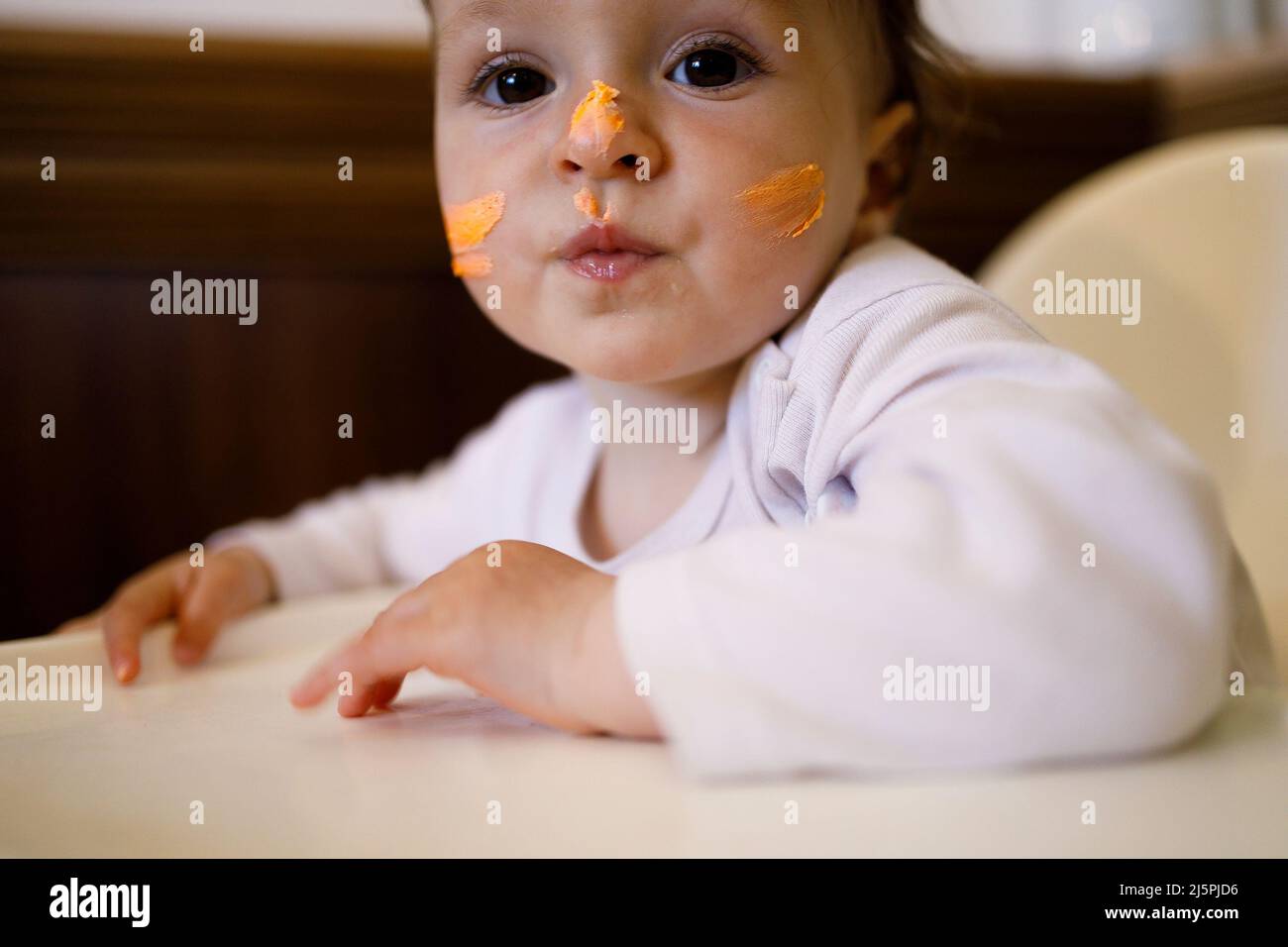 Weibliches kaukasisches Baby mit einer Schlagsahne auf ihrem Gesicht Stockfoto