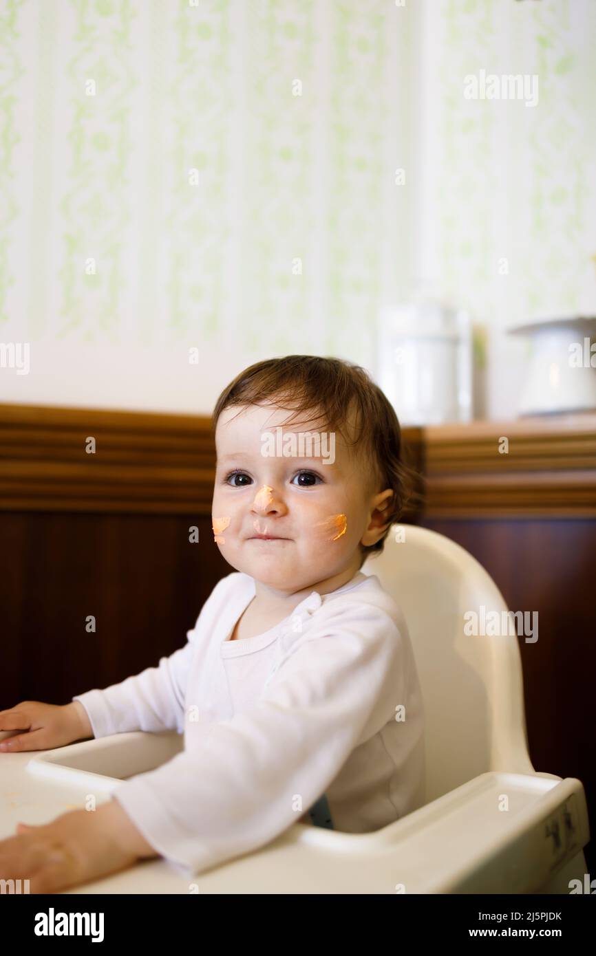 Lächelndes kaukasisches Baby, das auf einem Stuhl sitzt und ihren Geburtstag feiert Stockfoto