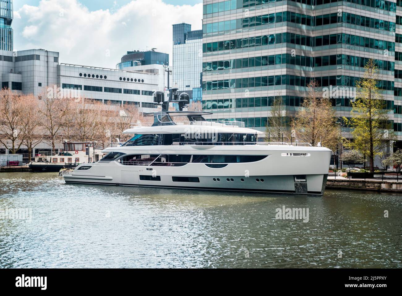 Weiße Superyacht vertäut in den Docks in Londons Canary Wharf. Ein super reicher Lebensstil. Stockfoto